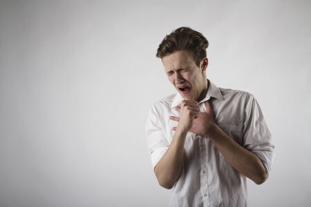 Young man in white is coughing. Pain and Symptoms concept. Infection.の写真素材