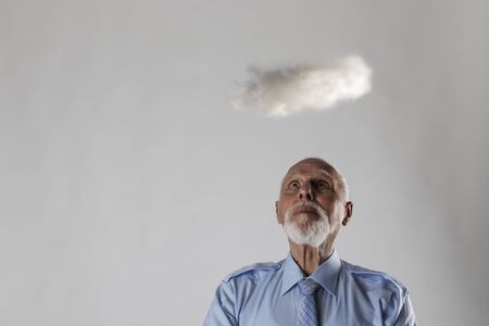 Old man and cloud. Old man is dreaming or thinking about something. Looking up.の写真素材