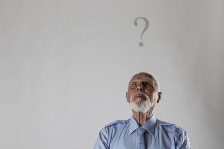 Old man is full of doubts and hesitation. Old man and question mark above head.の写真素材