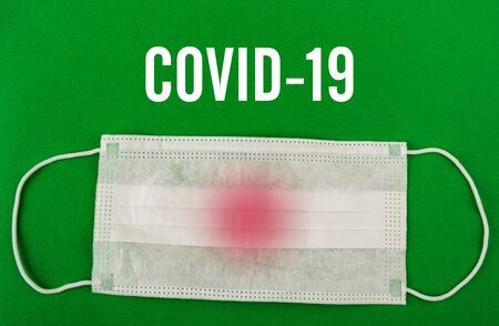 Medical protective mask on green background with Covid-19 text. Surgical face mask. coronavirus outbreak concept.の写真素材