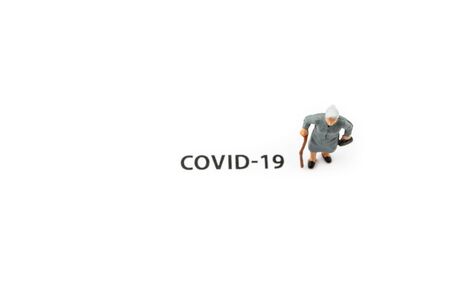 Old woman and coronavirus outbreak. Small figurine and text about Covid-19 on white background. Coronavirus prevention, social distancing and Quarantine concept.の写真素材