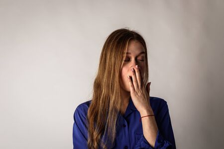 Sleepy young woman in blue. Girl yawning. Boredom and yawn.の写真素材
