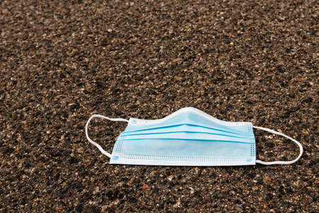 Medical protective mask on asphalt. Used medical mask thrown on the floor. Coronavirus outbreak...