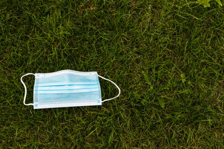 Medical protective mask on the grass. Used medical mask thrown on the ground. Coronavirus outbreak...