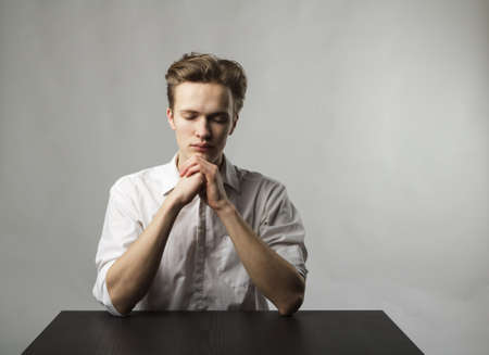 Tired young man is praying. Prayer and fatigue concept. Evening prayer.の写真素材