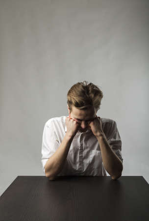 Tired young man. Frustration, overtime and fatigue concept. Feeling unwell. Bad condition and poor health.の写真素材