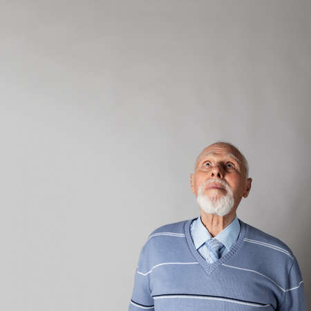 Old man is full of doubts and hesitation. Man is looking up.