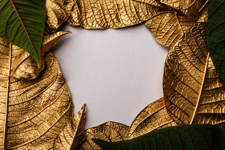 Golden Christmas flower leaves. Creative layout made of golden leaves with white paper card note....