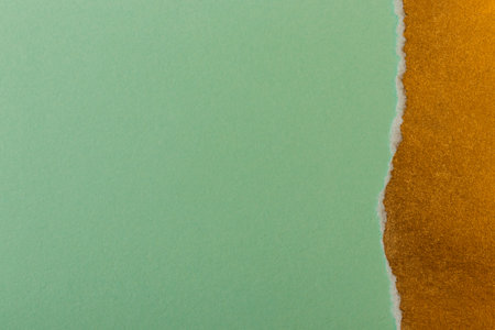 Torn golden paper on greenの写真素材