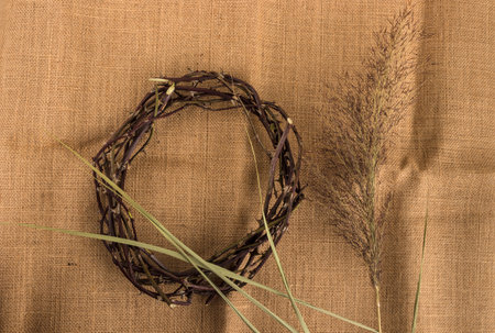 Crown of thorns and reed on brown textile background. Easter symbol with copy space.