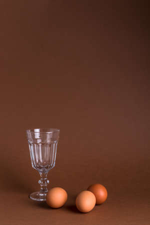 Glass bowl and eggs with copy space on brown background.の写真素材