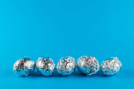 Eggs in aluminum foil on blue background with copy space. Easter symbol and background.