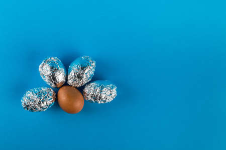 Eggs in aluminum foil on blue background with copy space. Easter symbol and background.の写真素材