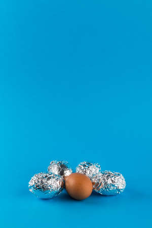 Eggs in aluminum foil on blue background with copy space. Easter symbol and background.の写真素材