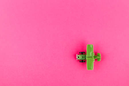 Small plastic airplane with copy space on pink background. Toy.