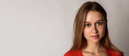 Portrait of happy young woman in red on gray background with copy space. Good mood and good vibes.