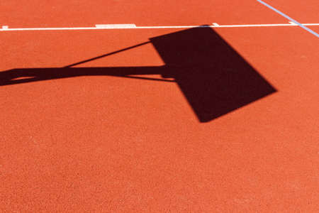 Basketball court lines. Brown field rubber ground with white lines and shadow of basketball board.