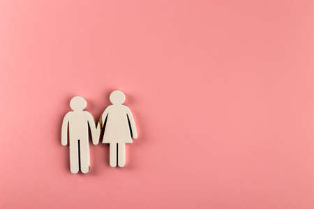 Broken family concept, divorce. Two wooden figurines on pink paper background.