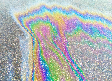 Gasoline stain on the roadway. Ecological disaster. Slick industry oil fuel spilling water pollution. Pavement with patches of gasoline and oil. Ecological catastrophe. Concept of environmental problems.の写真素材
