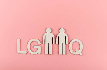 LGBTQ concept. Wooden figurines on pink paper background. Note about the LGBTQ community.の写真素材