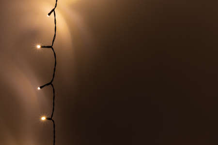 Garland. Christmas tree lights on dark wall. Rustic New Year black minimal background with copy...