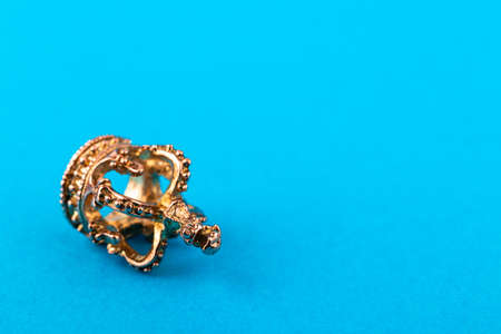 Small golden crown on blue paper background. Macro.の写真素材