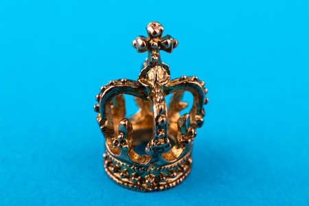 Small golden crown on blue paper background. Macro.の写真素材