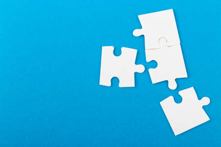 White jigsaw puzzle pieces on blue background. Texture photo with space for text. Teamwork conceptual photo.の写真素材