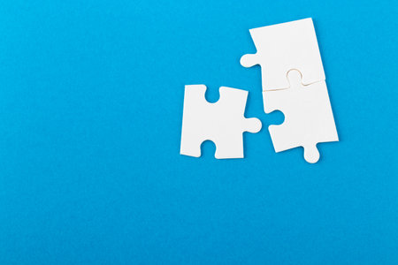White jigsaw puzzle pieces on blue background. Texture photo with space for text. Teamwork conceptual photo.の写真素材