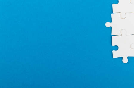 White jigsaw puzzle pieces on blue background. Texture photo with space for text. Teamwork conceptual photo.の写真素材