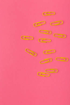 Colored paper clips. Yellow paper clips macro close up isolated on a pink background with copy...