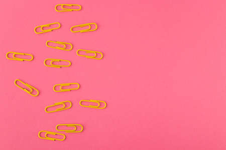 Colored paper clips. Yellow paper clips macro close up isolated on a pink background with copy space.の写真素材