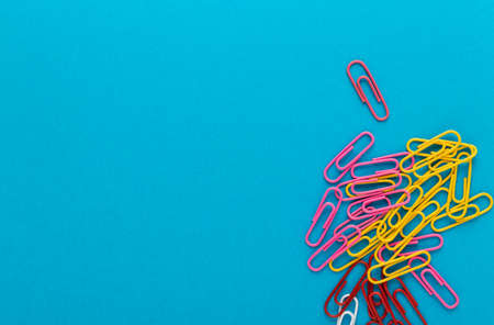Colored paper clips. Colored paper clips macro close up isolated on a blue background with copy space.の写真素材