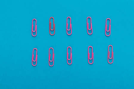 Colored paper clips. Pink paper clips macro close up isolated on a blue background with copy space.の写真素材