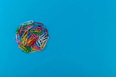 Circle of colored paper clips. Colored paper clips macro close up isolated on a blue background with copy space.の写真素材