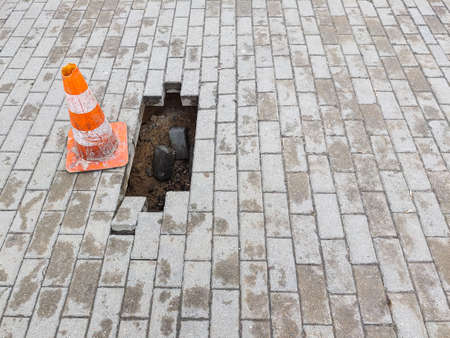 Warning sign and a hole on the sidewalk. Damaged pedestrian zone.の写真素材