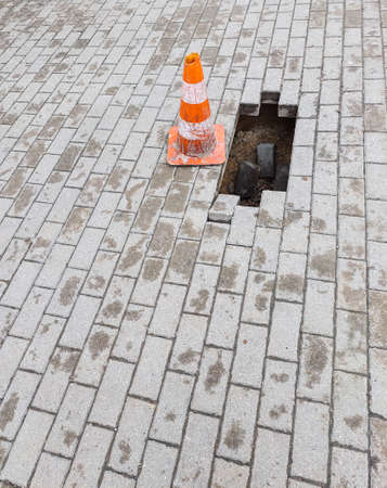 Warning sign and a hole on the sidewalk. Damaged pedestrian zone.の写真素材