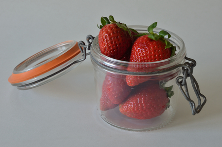 Red strawberries in open old glas jar on white backgroundの写真素材