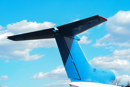 Tail of a jet airplane in front of sky background with flying airplane track, bottom viewの写真素材