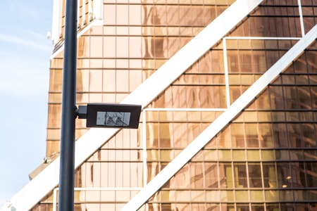 Modern street lights illuminated at day light against glass and steel office buildingsの写真素材