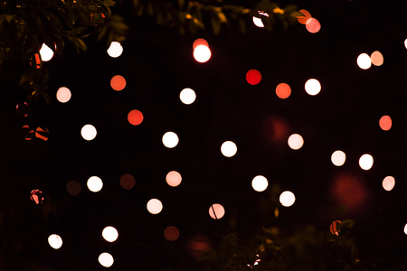 Abstract defocused red glittering shine bulbs lighting bokeh on blurred green background in colorful...