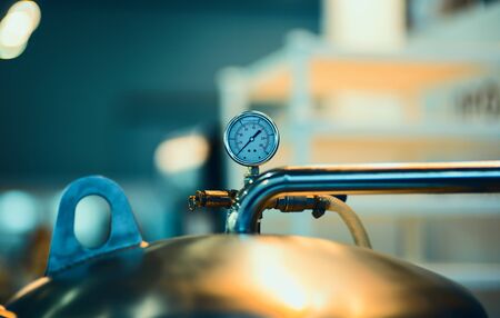 pressure gauge psi meter in pipe and valves of water system industrial focus left closeup white light defocus blur background.の写真素材