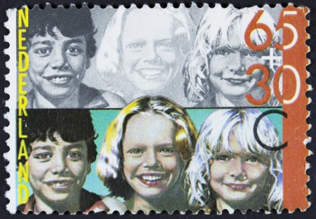 NETHERLANDS - CIRCA 1981  stamp printed by Netherlands, shows Coloured and black-and-white Portraits of children, circa 1981 のeditorial素材