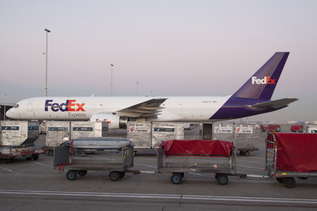 Amsterdam the Netherlands 18 february 2015: FedEx Boeing 757 200 on Schiphol cargo to be loaded with goods with cargo carts in the foregroundのeditorial素材