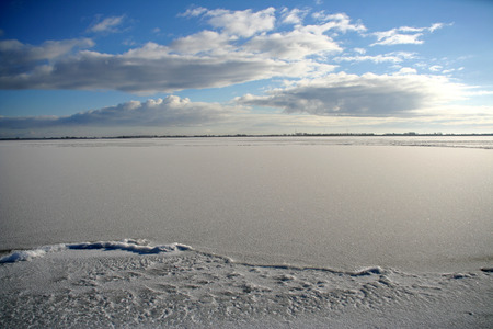 Frozen IJsselmeer with clouds and blue skies on a beautiful sunny winter day.の写真素材