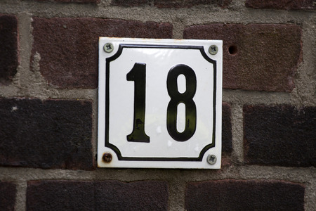 Enameled house number eighteen on a red brick wallの写真素材