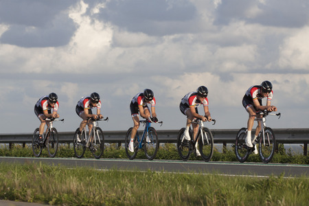 ENKHUIZEN, THE NETHERLANDS - JULY 2, 2016: Cyclists ride in a row, during a time trial contest for cyclists on the car dike Lelystad and Enkhuizenのeditorial素材