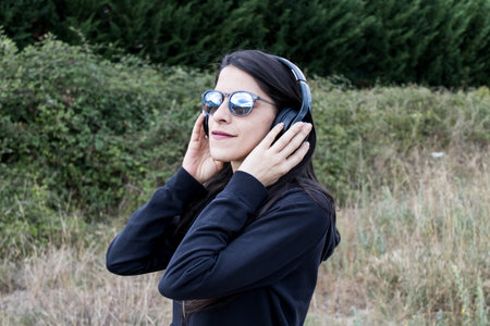 Women closeup outdoors with headphones and sunglassesの写真素材
