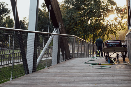 municipal employee cleaning a wooden bridge with a pressure washing machineの写真素材