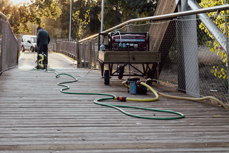 municipal employee cleaning a wooden bridge with a pressure washing machineの写真素材